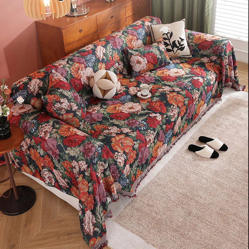 A romantic floral jacquard sofa blanket draped over a sofa with decorative pillows and black and white socks.