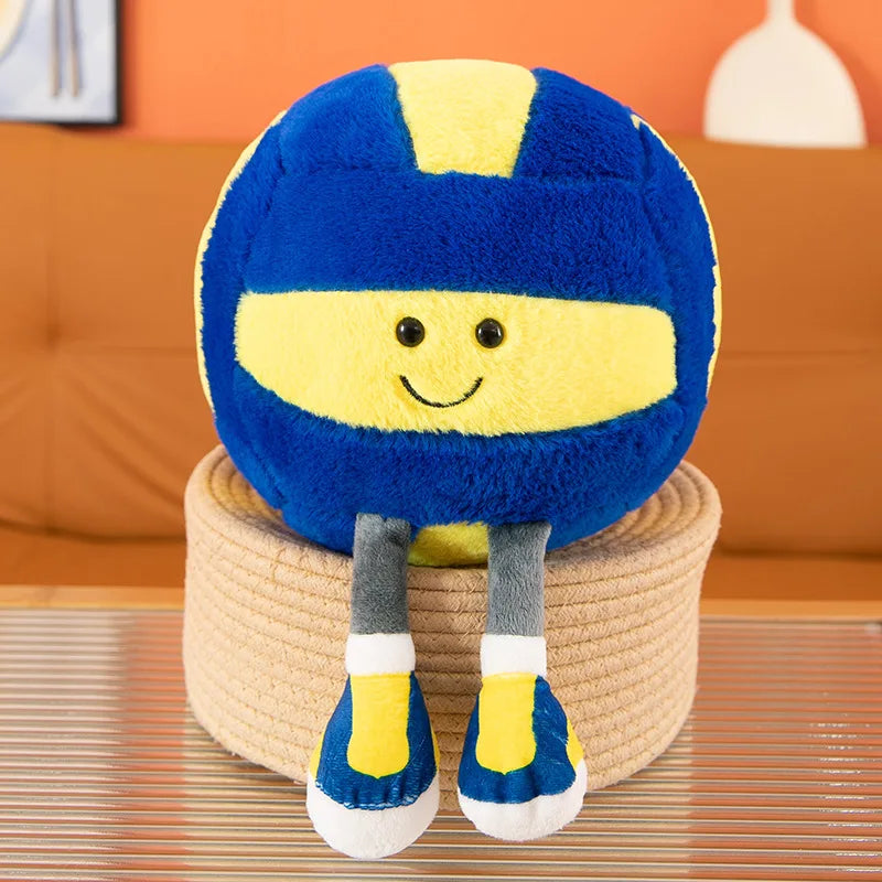 A blue and yellow sports ball plush toy with a smiling face, sitting on a beige cylindrical stand.