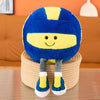 A blue and yellow sports ball plush toy with a smiling face, sitting on a beige cylindrical stand.
