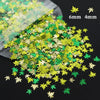 A pile of shiny holographic star sequins in gold and green colors, showing different sizes.