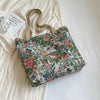 A floral patterned corduroy tote bag resting on a white fabric background.