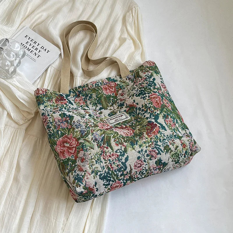 A floral patterned corduroy tote bag resting on a white fabric background.