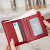 A hand holds a red leather compact zippered wallet with card slots and a VIP display.
