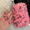 A hand is holding a skein of pink and purple variegated yarn for knitting or crochet.