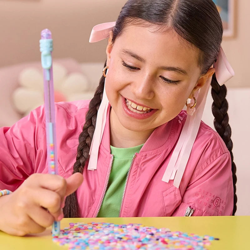 A girl is making friendship bracelets using colorful beads and string on a yellow table.