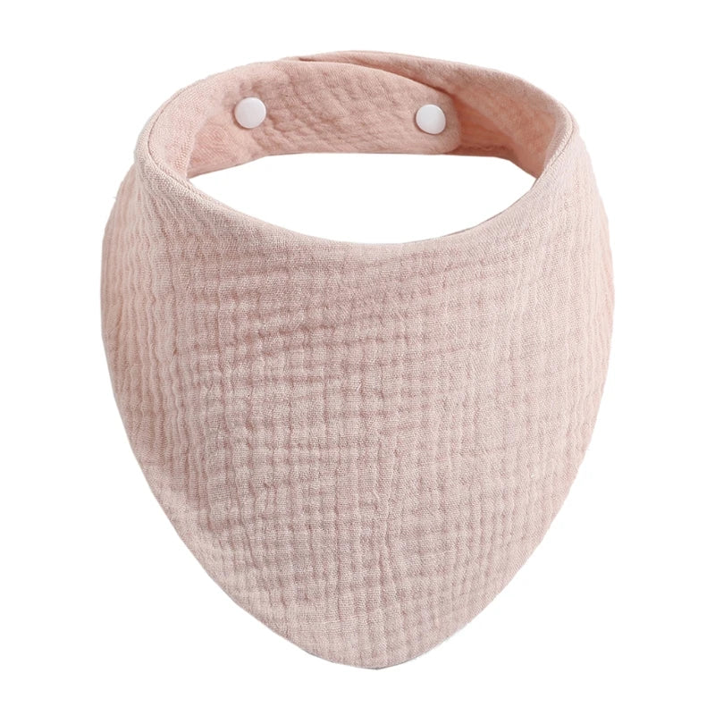 A light pink organic cotton muslin baby bib with a textured surface and adjustable band.