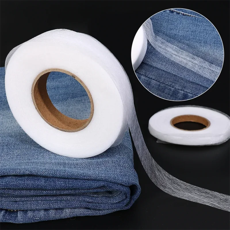 Roll of white double-sided iron-on adhesive tape next to a folded denim fabric and a circular close-up view.