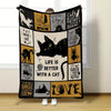 A black flannel throw blanket featuring various cat-themed quotes and illustrations on a light background.