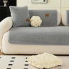 Housse de canapé sherpa gris clair avec coussins décoratifs et accent tricoté blanc sur un canapé de salon.