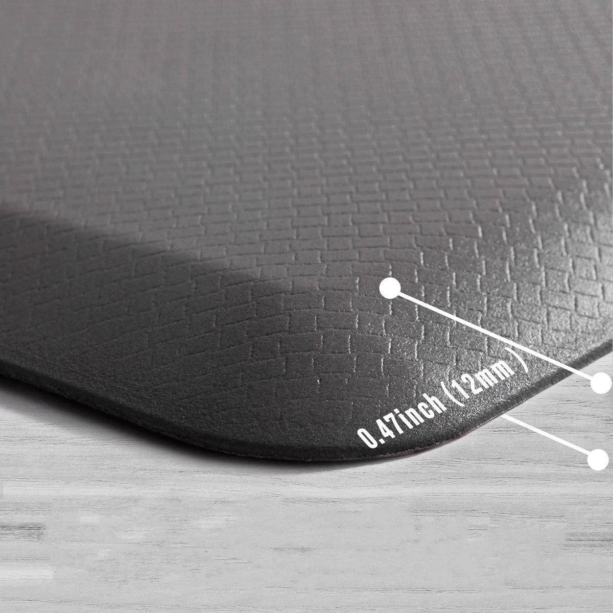 A black anti-fatigue standing mat with a waterproof non-slip surface shown on a wooden floor.