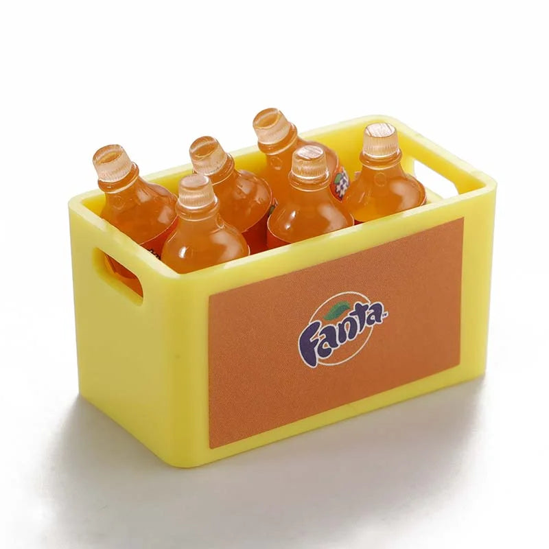 A yellow plastic container holds three glass bottles filled with an orange liquid, used as decorative accessories for an RC c