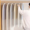 A person is hanging a transparent zippered garment bag for clothes storage on a wooden rack.