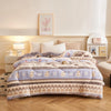 A beige and purple plush throw blanket with a patterned design is displayed on a bed.