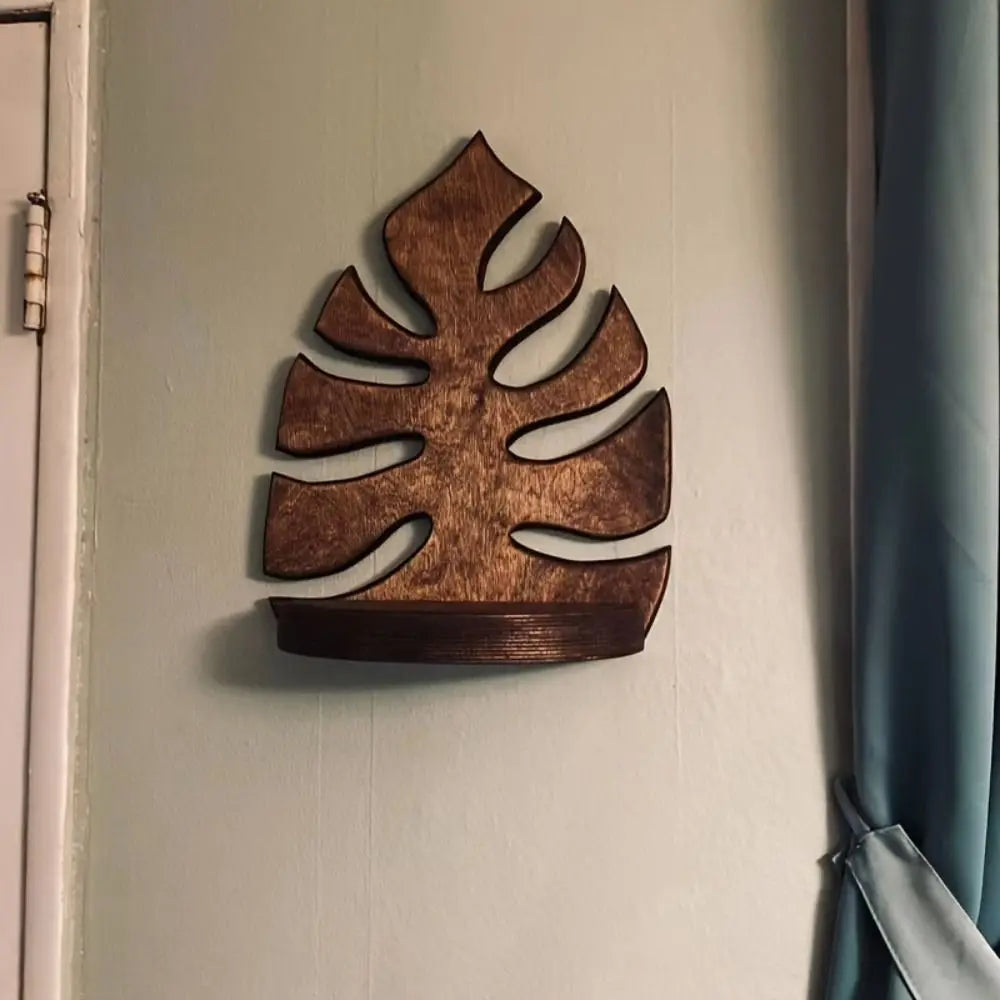 A rustic wooden wall-mounted storage rack shaped like a tropical leaf, mounted on a light-colored wall.