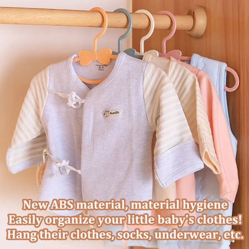 A set of baby clothes hangers displaying various light-colored and striped garments for organization.