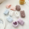 A collection of soft, fuzzy microfiber wrist sweatbands and scrunchies in shades of pink, purple, lavender, and gray are disp