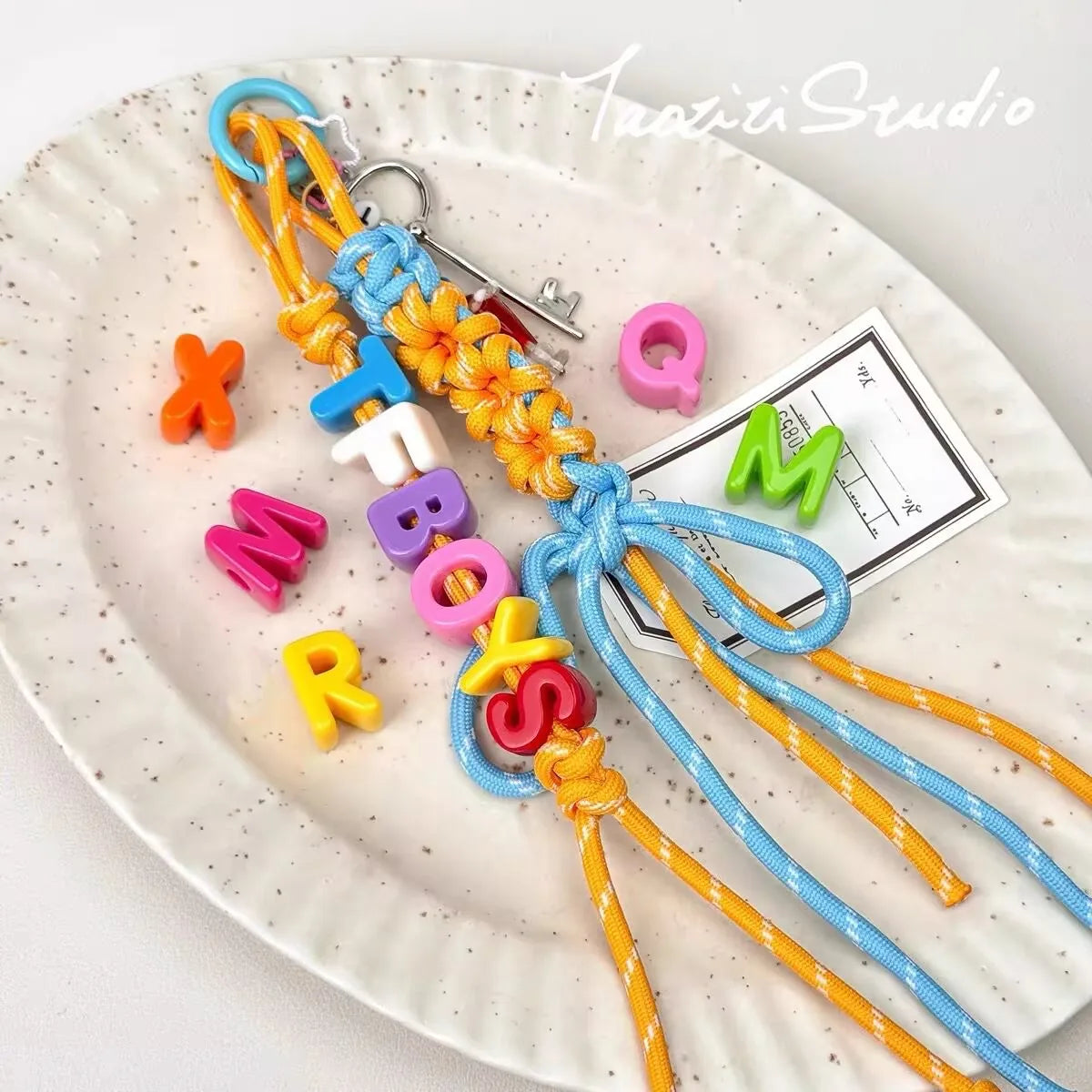 A collection of 10 mixed alphabet letter beads in various colors like orange, blue, pink, and yellow arranged on a white plat