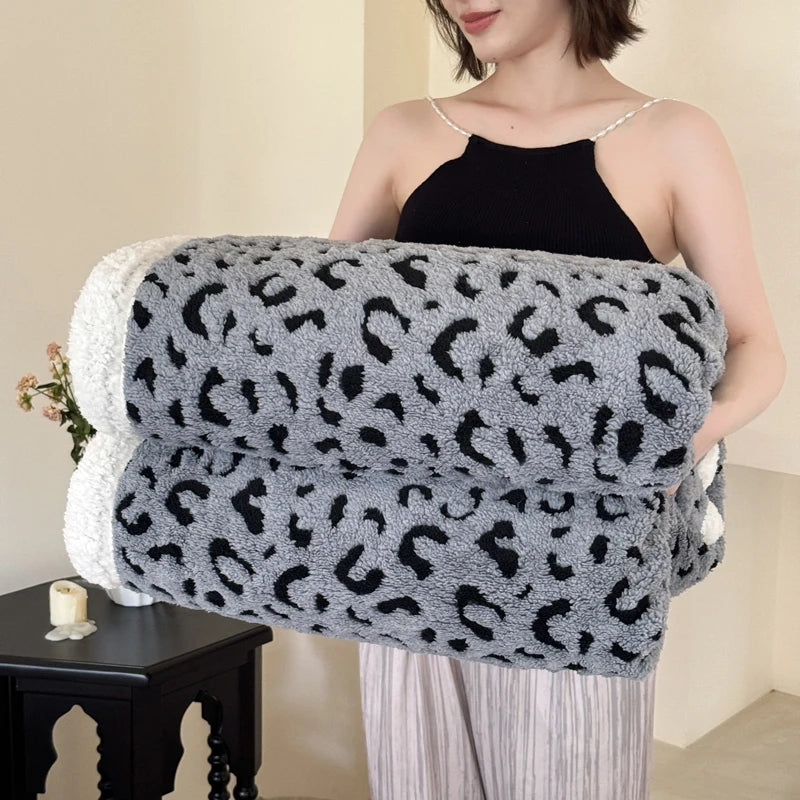 A woman holds a gray and black leopard print plush jacquard throw blanket.
