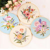 A collection of five round embroidery hoops featuring colorful floral designs in pink, purple, and orange threads.