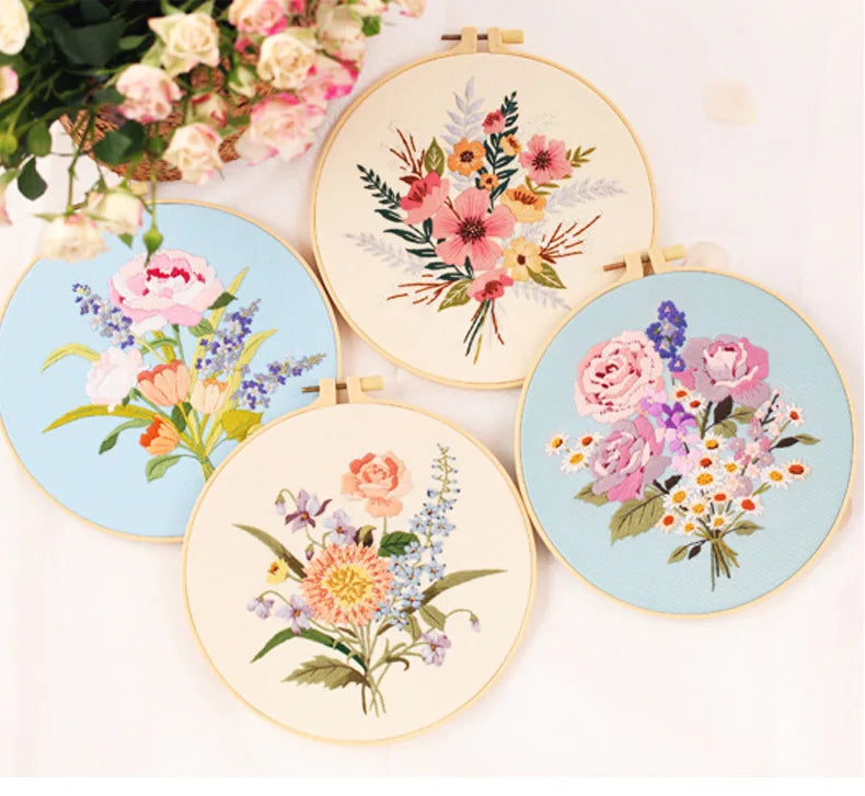 A collection of five round embroidery hoops featuring colorful floral designs in pink, purple, and orange threads.