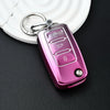 A pink soft TPU car key cover with a metal ring attached, resting on a white surface.