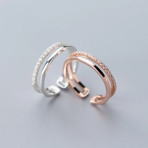 Trois bagues en argent sterling empilées, dont une bande ton or blanc et une bande ton or rose avec de petites pierres.