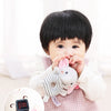 A baby is holding a soft plush rattle toy with a cartoon animal design.