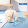 A blue ergonomic crochet hook with a bee design is shown next to a ball of light-colored yarn.