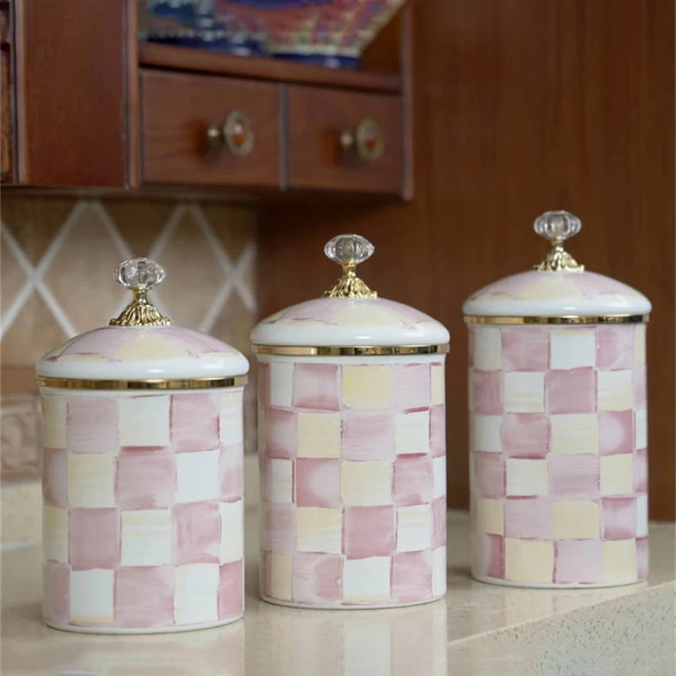 Three decorative porcelain storage jars with a pink and cream checkerboard pattern on a light surface.
