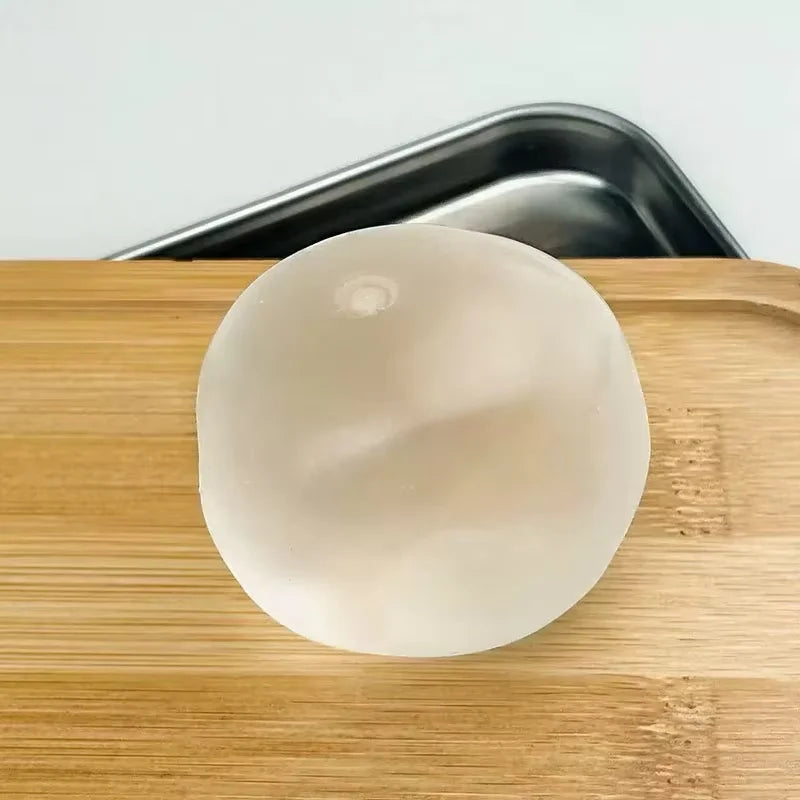 A round, translucent white squishy stress relief toy resting on a wooden cutting board.