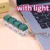 A green LED mechanical keychain fidget toy with custom keycaps resting on a laptop keyboard.