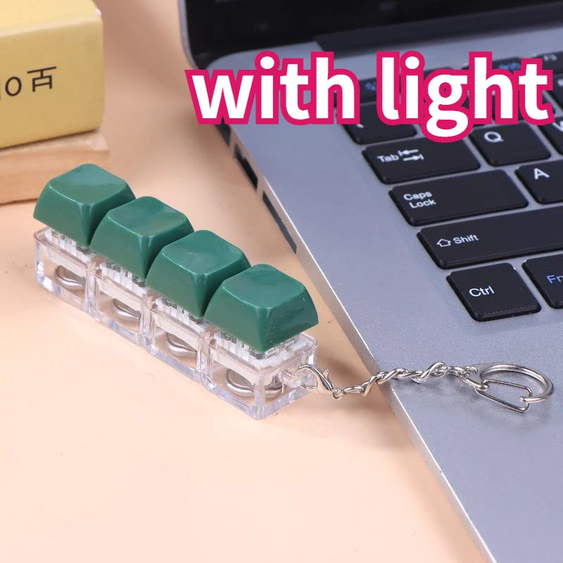 A green LED mechanical keychain fidget toy with custom keycaps resting on a laptop keyboard.