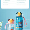 A blue water bottle featuring a bear cartoon design with an orange lid and pink strap, displayed on a white surface.
