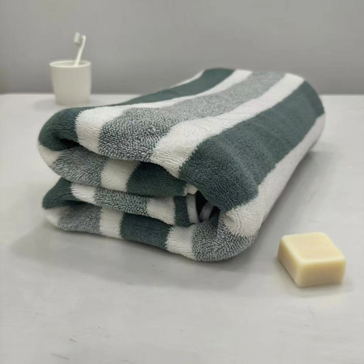 A folded striped gray and white quick-dry bath towel resting on a white surface.