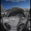 A close-up view of a Lexus steering wheel covered with black carbon fiber texture grips.
