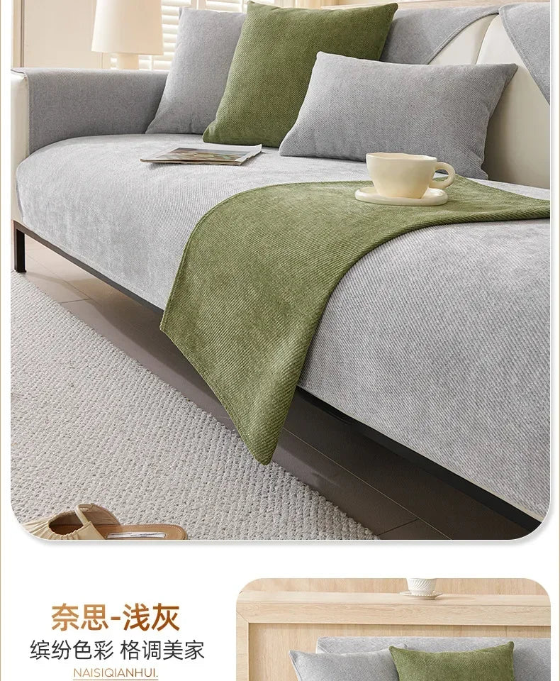 A light gray sofa is covered with a moss green non-slip fabric and features decorative pillows and a tea cup.