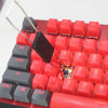 A close-up view of a red mechanical keyboard featuring various keycaps and a black puller tool.