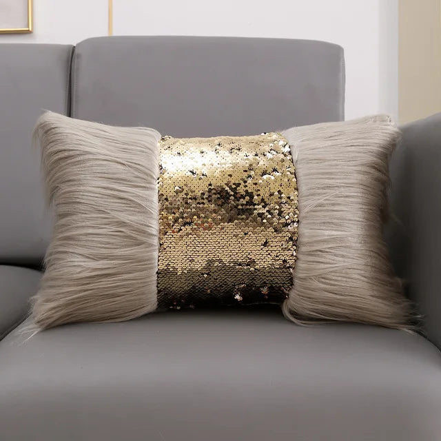 A decorative pillow featuring a silver and gold sequin fabric surrounded by fluffy gray fur trim.