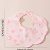 A pink soft cotton baby bib with a ruffle trim and heart pattern, shown flat.