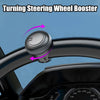A black turning steering wheel booster device is shown being attached to a car steering wheel.