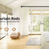 A set of black decorative curtain rods installed in a bright room with large glass doors and white curtains.