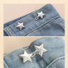 Close-up of a denim fabric showing silver star metal belt buckles used as decorative pins.