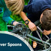 A child is using a tire lever spoon on a bicycle wheel.