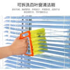 An orange dusting brush is cleaning the slats of a blue horizontal blind.