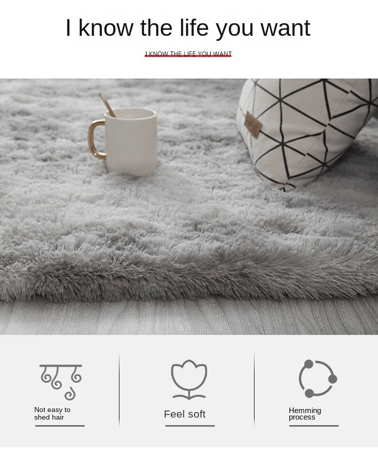 Nahaufnahme eines grauen, tiegedyedeten Teppichs mit einer weißen Tasse und einem gemusterten Kissen auf einem Holzfußboden.