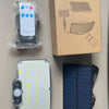 A box containing a solar-powered motion sensor security flood light, a remote control, and a standalone solar panel.