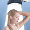 A woman is under a high-pressure shower head, showing water spray and foam.