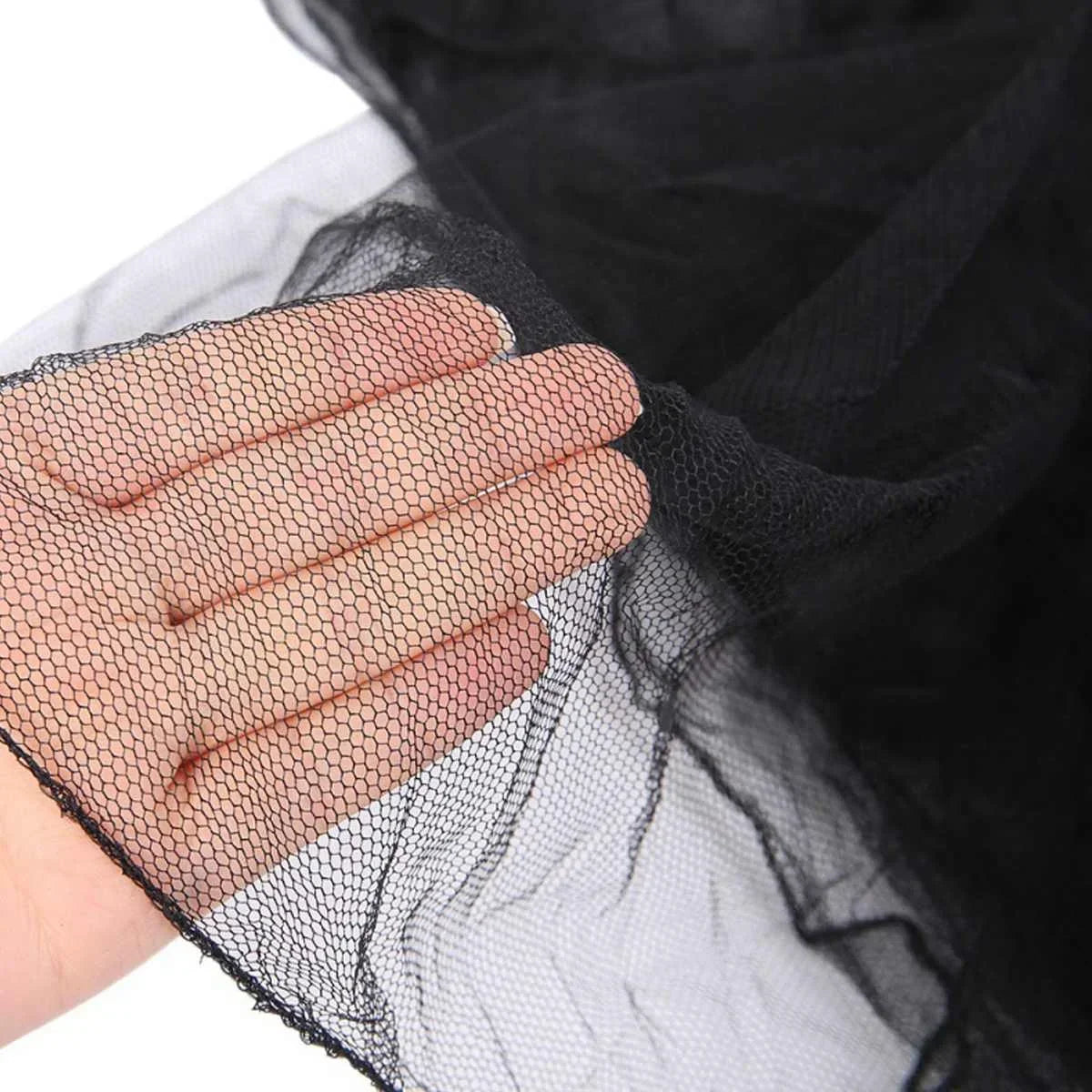 Close-up of a hand holding black lace canopy mosquito net fabric