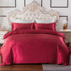 A luxurious deep red silky duvet cover set displayed on a bed with a white upholstered headboard.