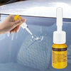 A hand applies a yellow liquid from a bottle onto a windshield to repair cracks and chips.